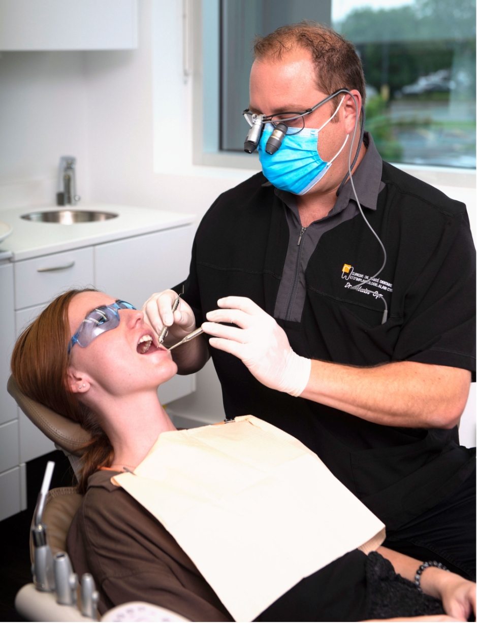 Dentist Alain Cyr conducting an examination to assist a patient with her dental rehabilitation