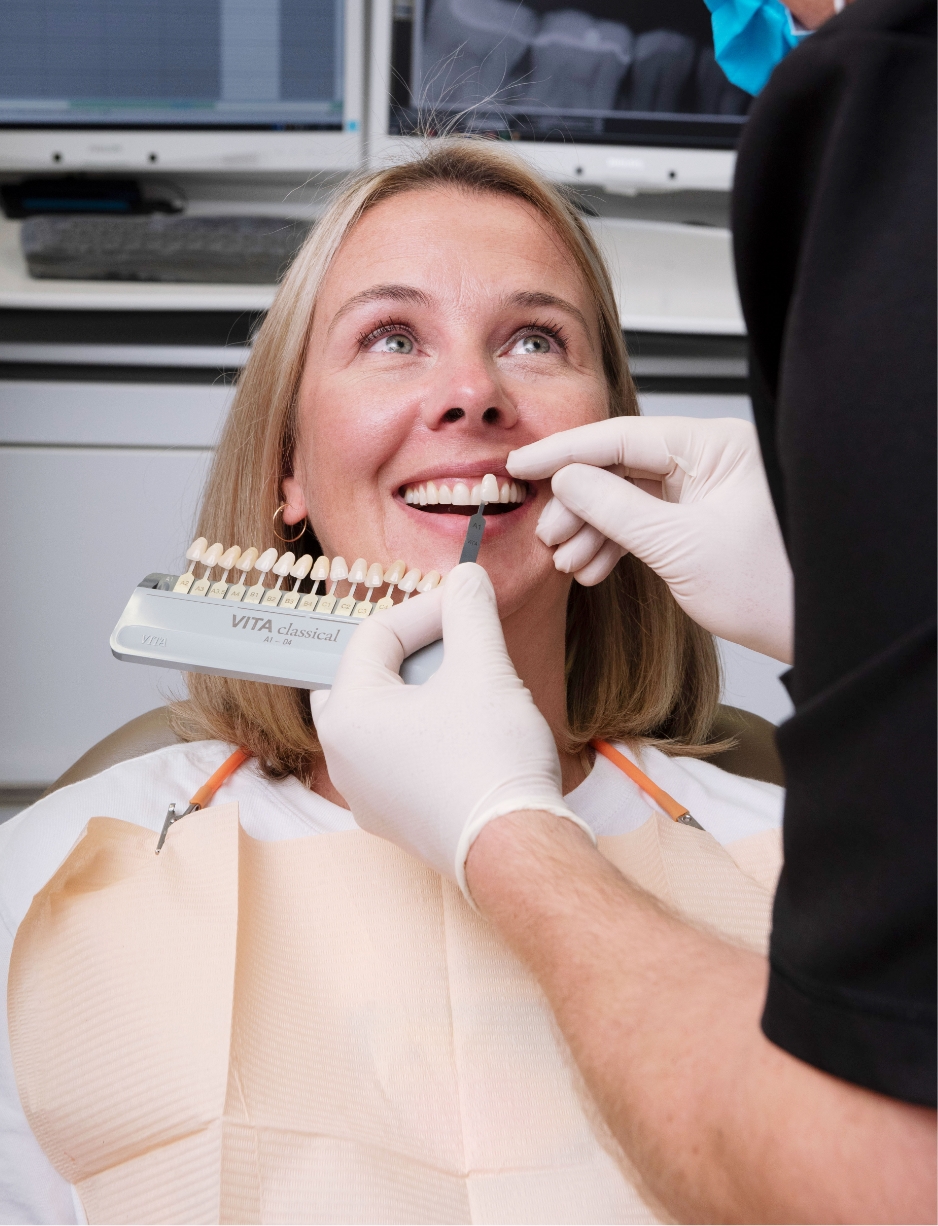 a woman patient looking at color options for her veneers at the dental clinic