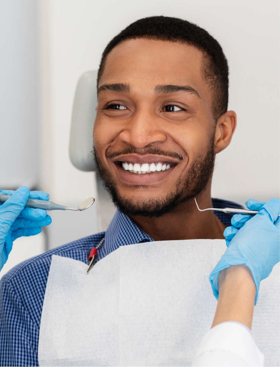 a man sitting in the dental chair with a beautiful white smile receiving dental services