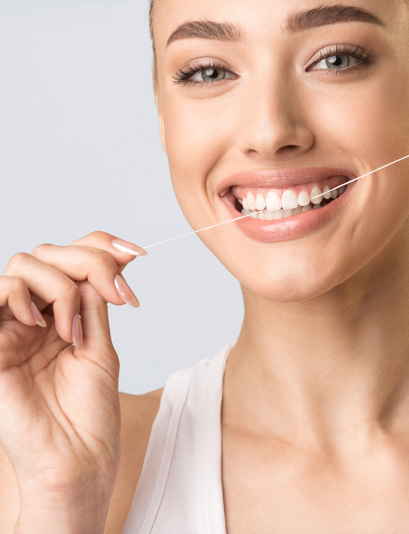 An image of a woman flossing, which is a good practice after a dental implant
