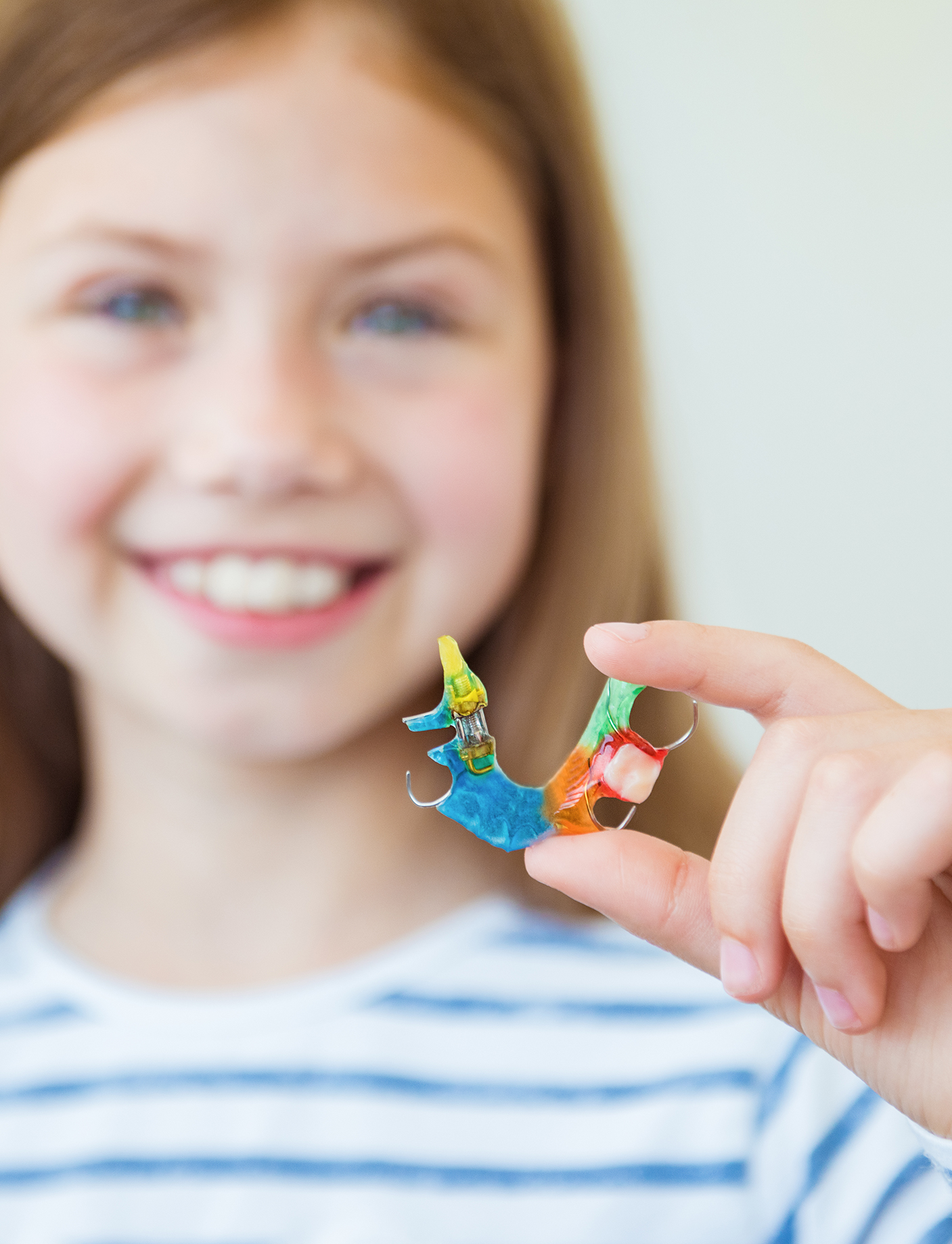 A little girl holding in her hand an orthodontic dental applicance